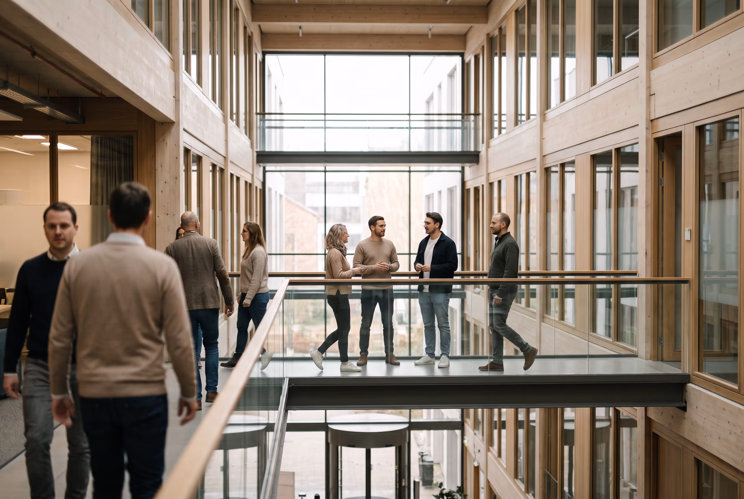 Colleagues crossing a wide office atrium between meetings.